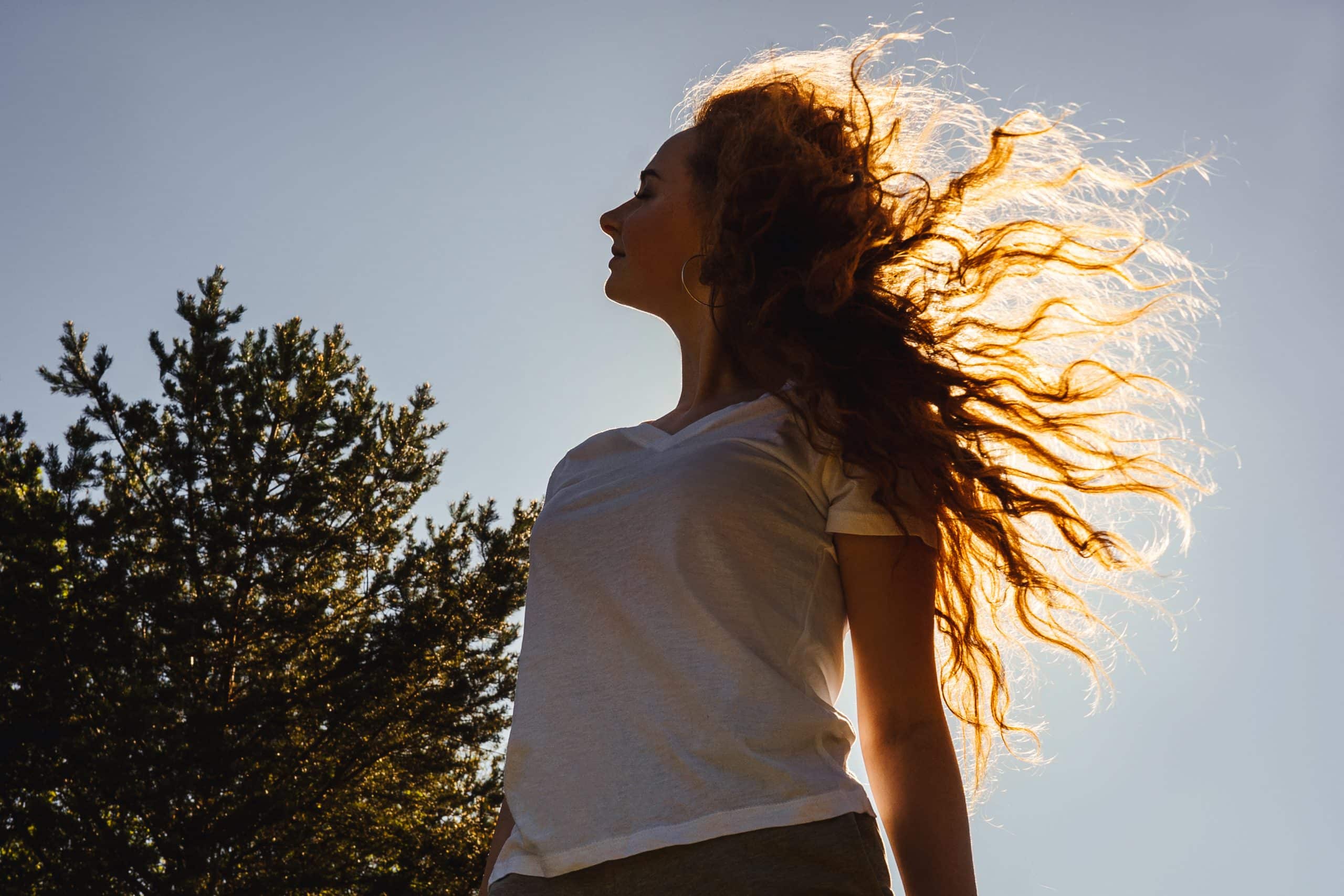 Young happy woman with long curly hair in sunshine. Country life.