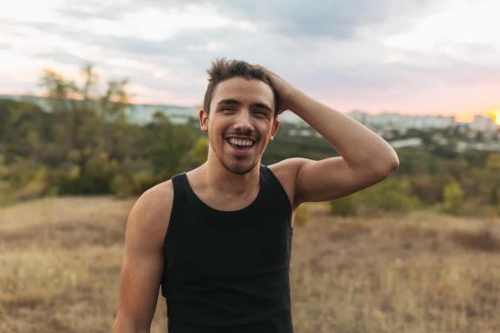 Happy smiling man Portrait of a happy smiling man on nature and city background. Good-looking young man love life.